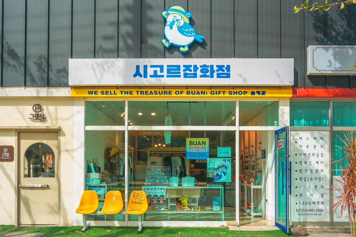 시고르잡화점 외관. 캐릭터와 청색 상호, 노란 좌석, 투명한 쇼윈도